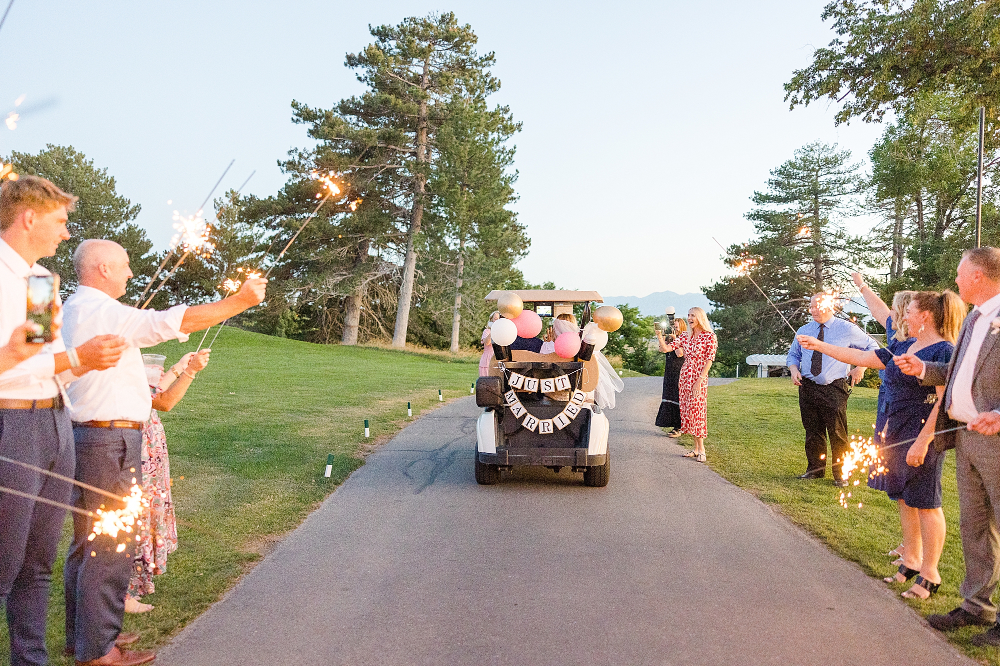 Colorful sparklers light up the night sky as the couple makes their grand exit in a decorated golf cart.
