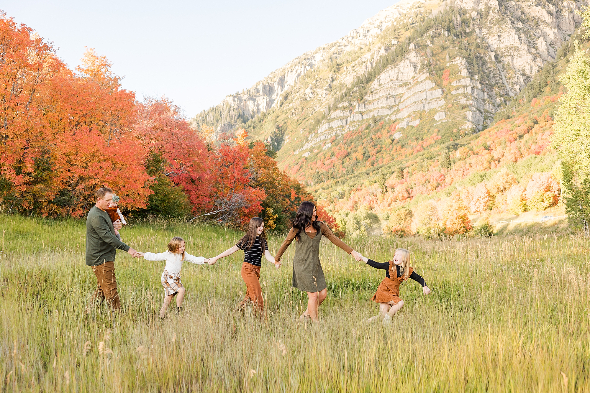 Family walking across a vast field with the beautiful Utah mountains in the background.